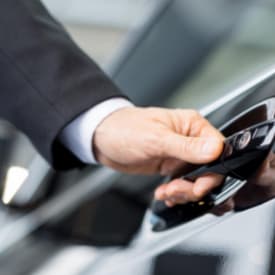 Contact Limo chauffeur opening luxury SUV door for bridal party — Kenosha wedding transportation