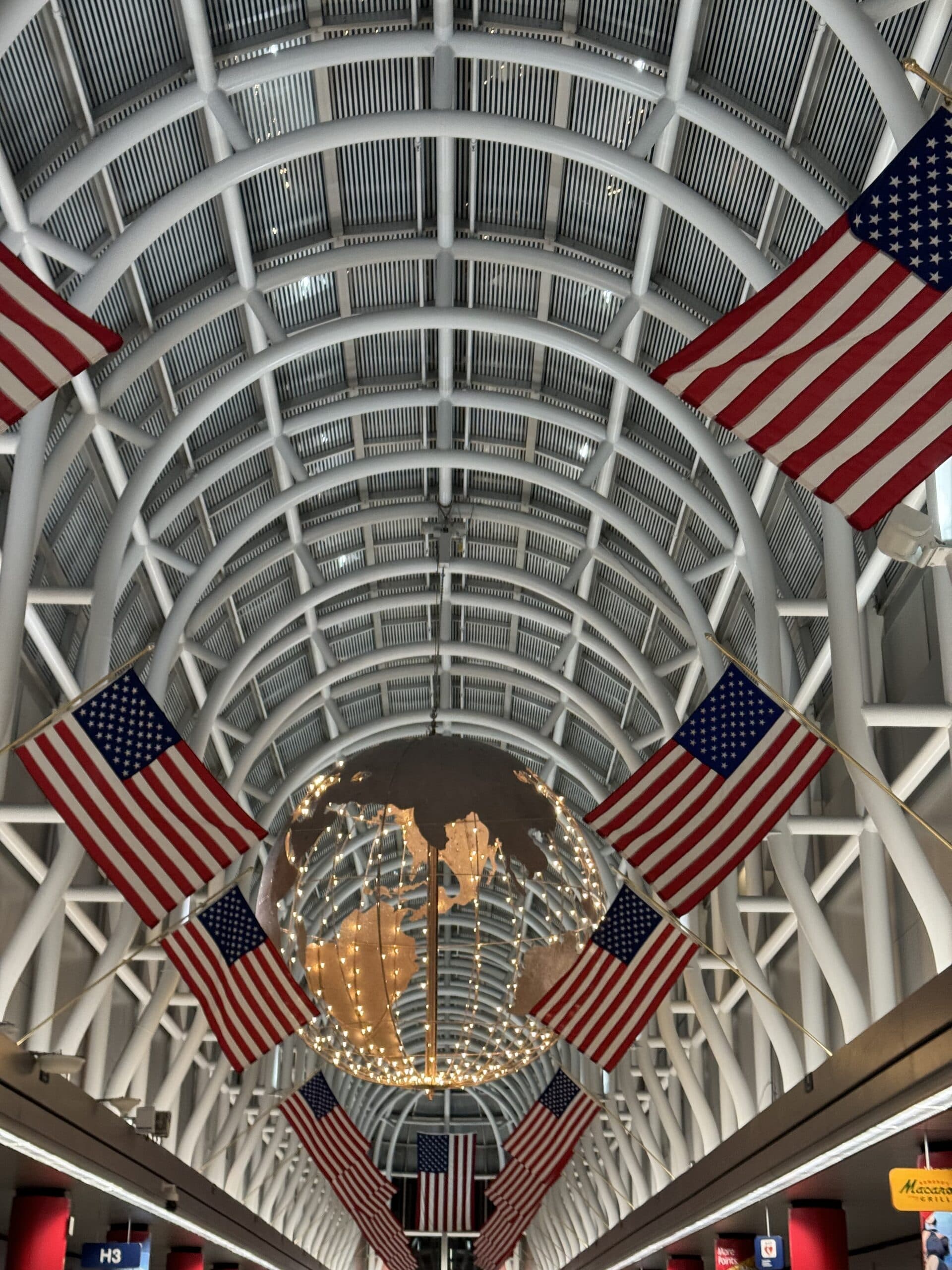 O'Hare International Airport interior Terminal H3 with American flags and globe sculpture, Contact Limo pickup point